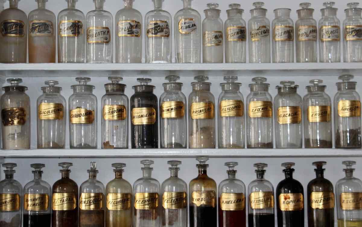Shelves of apothecary jars with gold ingredient labels