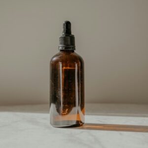 Amber glass dropper bottle of hair treatment oil in soft light