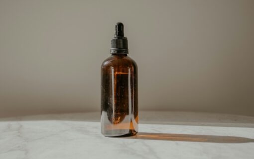 Amber glass dropper bottle of hair treatment oil in soft light