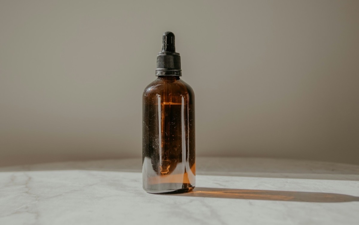 Amber glass dropper bottle of hair treatment oil in soft light