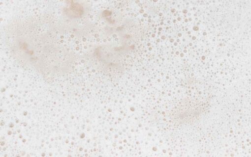Close-up of soft cream-coloured shampoo lather and fine bubbles